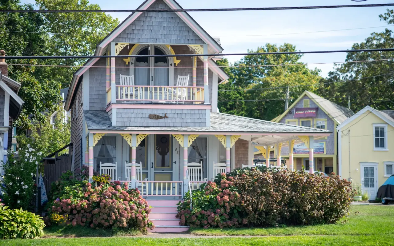 Grey and pink Victorian gingerbread cottage with a porch and hydrangeas in Oak Bluffs