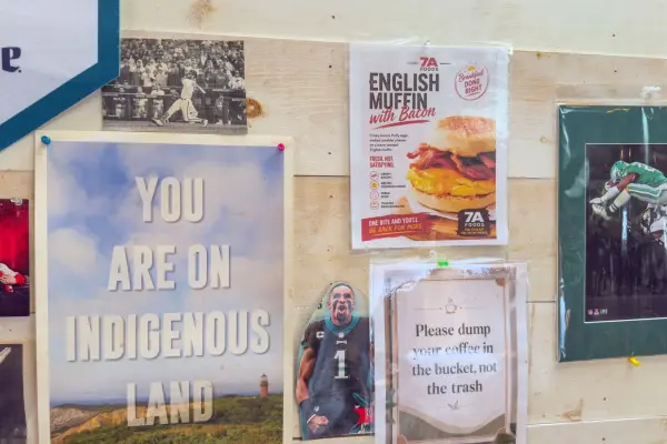 The deli wall at 7a Foods, including its You Are On Indigenous Land poster