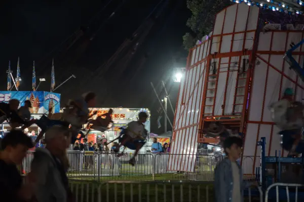 Swings caught mid-flight over the midway, ice cream stands glowing behind