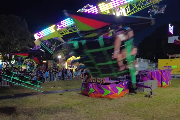 A spinning ride lit up on a fair night