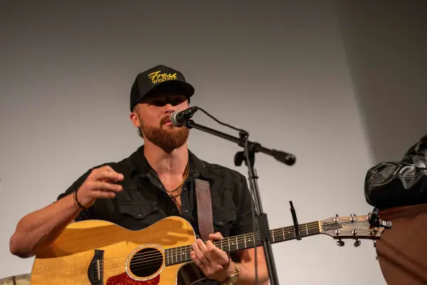 Austin G at the microphone, one hand off the guitar