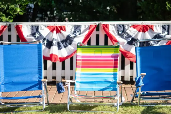 Empty beach chairs saving spots along a bunting-draped fence before the Edgartown Fourth of July parade