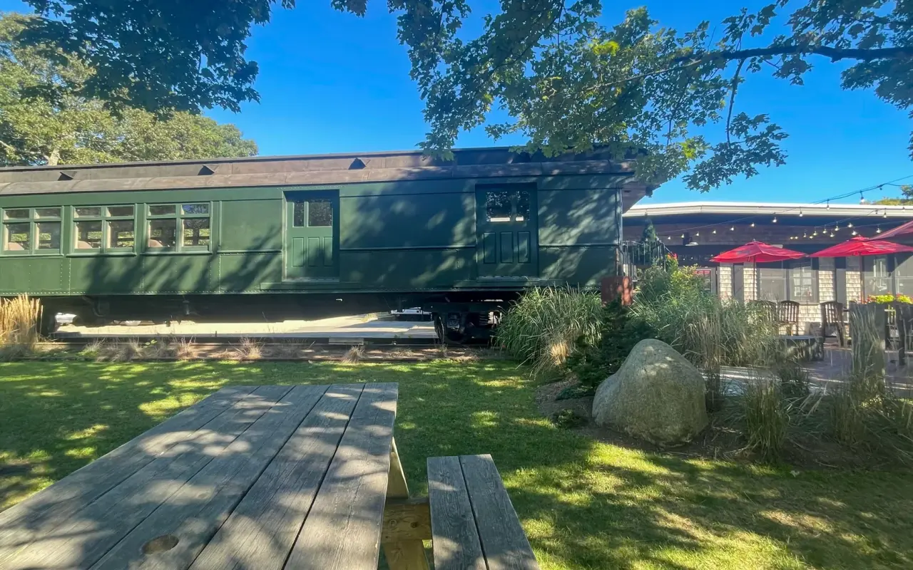 A green railway car parked beside picnic tables at the Black Dog Bakery Cafe in Vineyard Haven