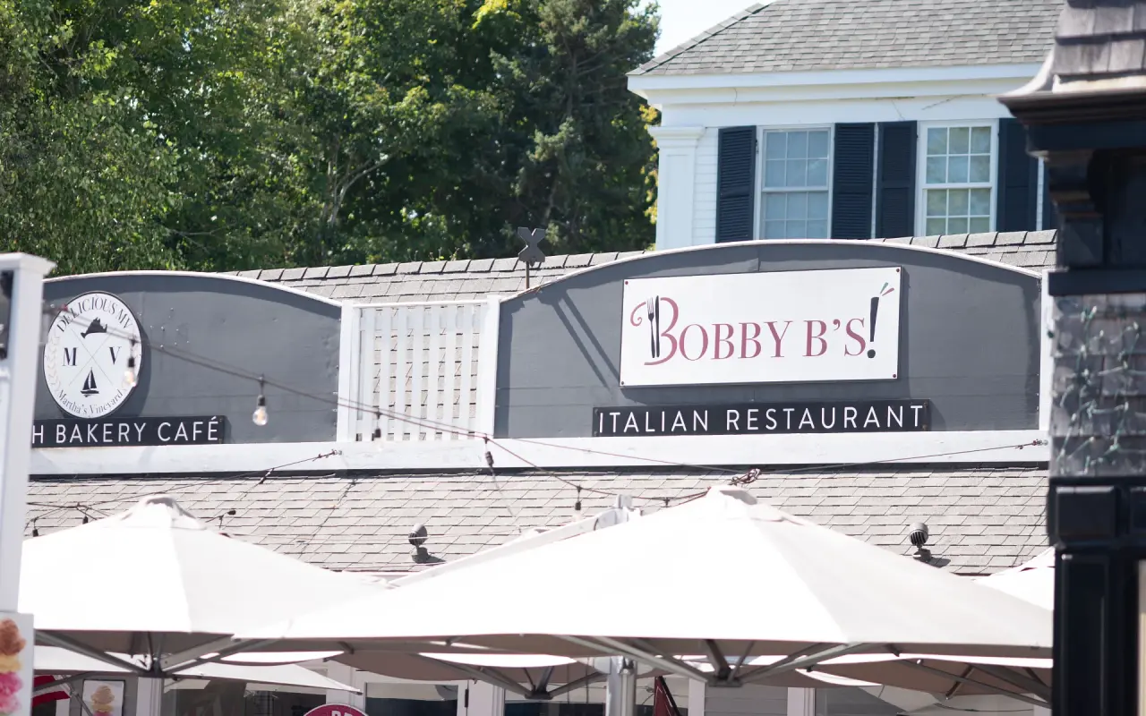 Bobby B's Italian Restaurant sign above white patio umbrellas, a bakery cafe sign to the left