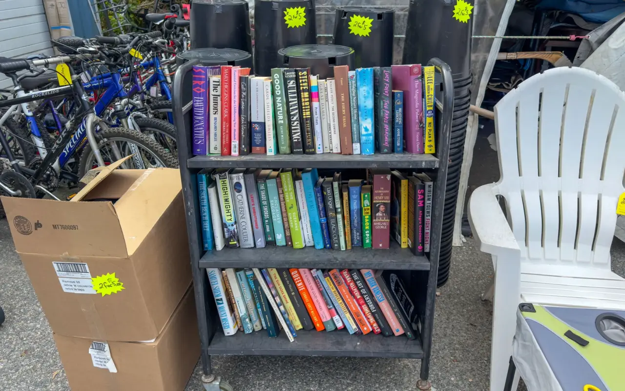 Cart of used books with bicycles and planters outside Chicken Alley Thrift Shop in Vineyard Haven
