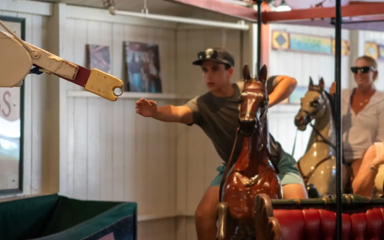Rider stretching for the brass ring arm on the Flying Horses Carousel in Oak Bluffs