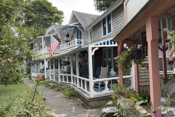 A row of Campground porches: blue rockers, hanging baskets, a coral porch in front