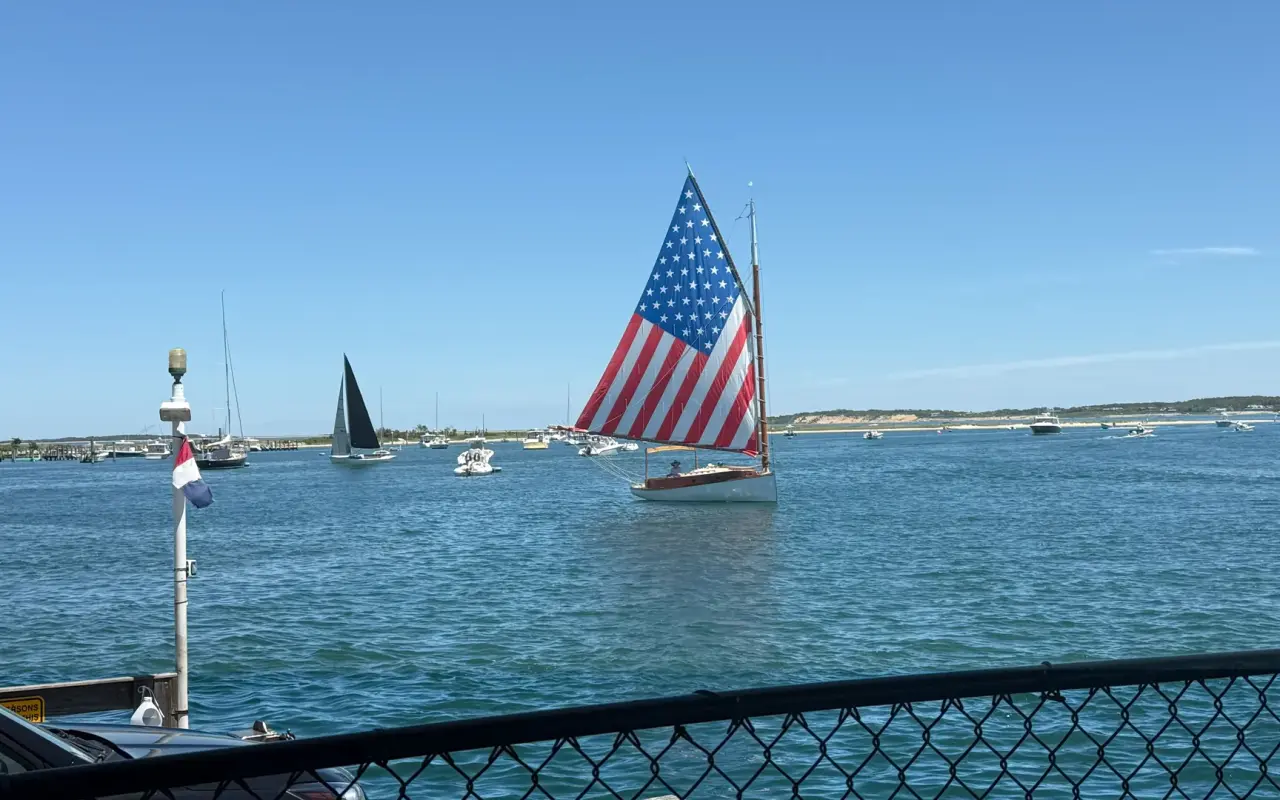 A catboat with an American flag sail in Edgartown harbour