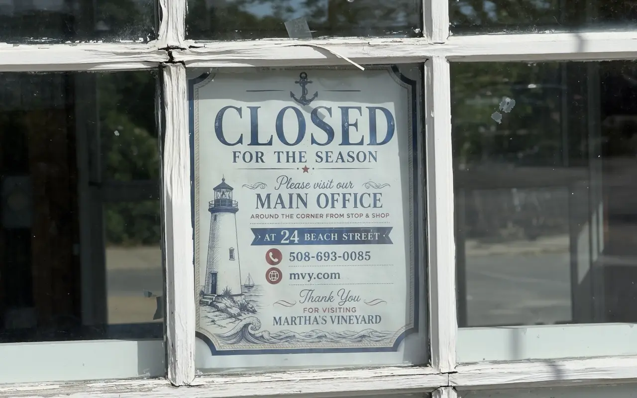 A Closed for the Season sign in a white-framed window, with an anchor and a lighthouse drawing, pointing to the main office at 24 Beach Street, 508-693-0085, mvy.com