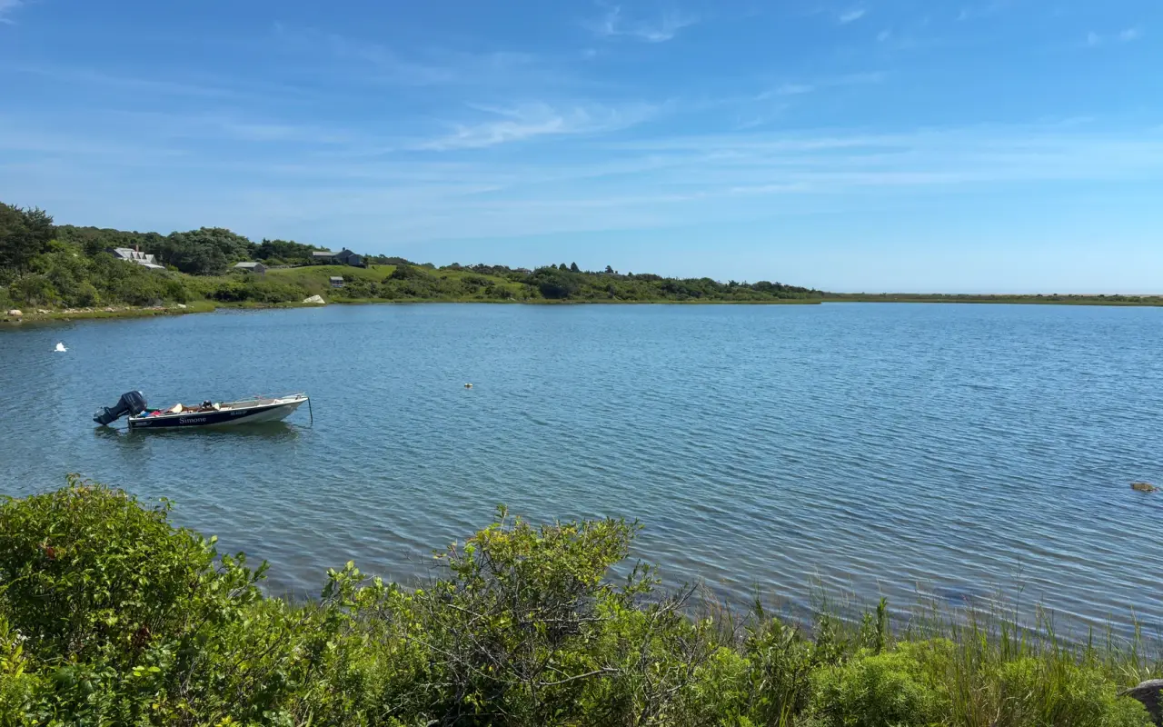 Calm Chilmark Pond with a single small boat on Martha's Vineyard