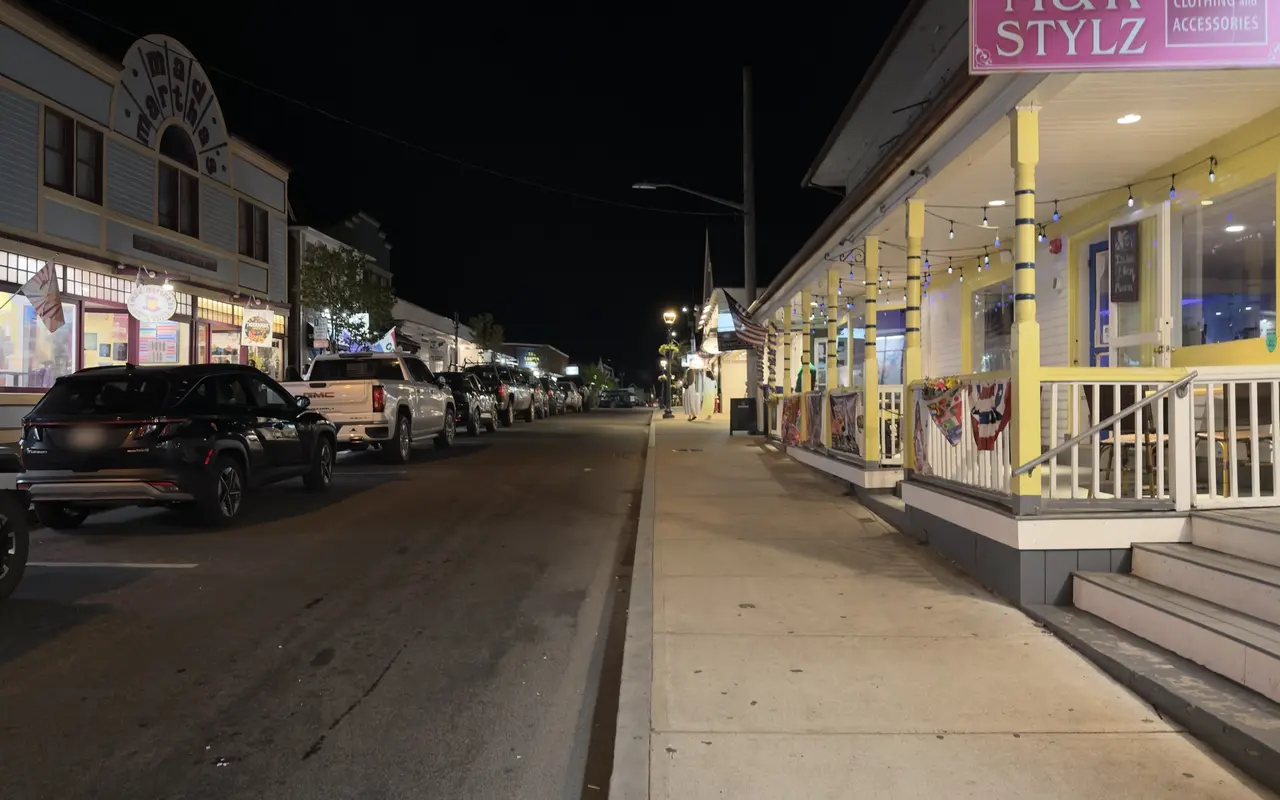 Circuit Avenue in Oak Bluffs on a September night: the Mad Martha's facade lit on the left, parked cars, and a yellow-trimmed shop porch with string lights on the right