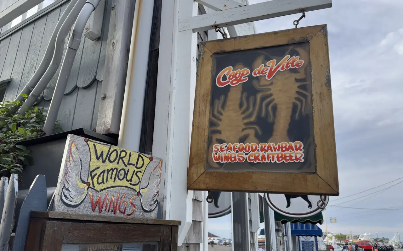 Hanging wooden Coop de Ville sign with two lobsters and a painted World Famous Wings board below it