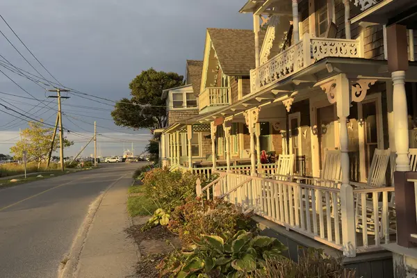 Cottages on the harbor side at golden hour, masts at the end of the road