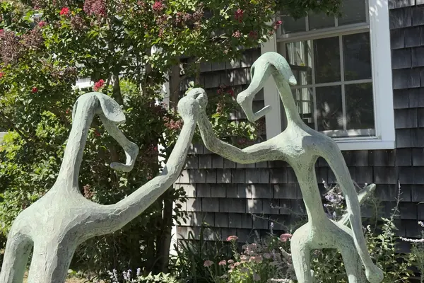 The dancing figures up close, crape myrtle behind them