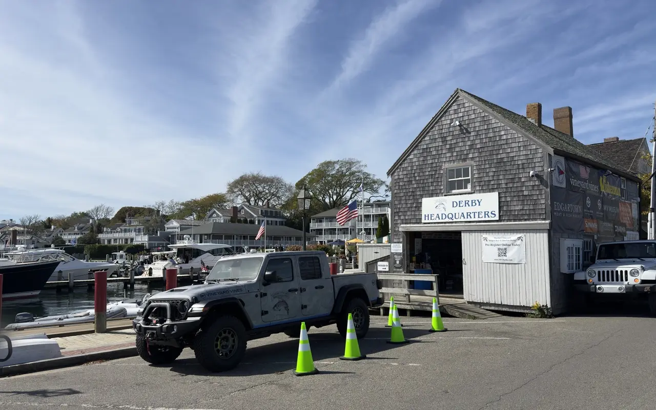 Derby Headquarters building on Dock Street in Edgartown with a pickup truck, traffic cones and the harbor full of boats beyond