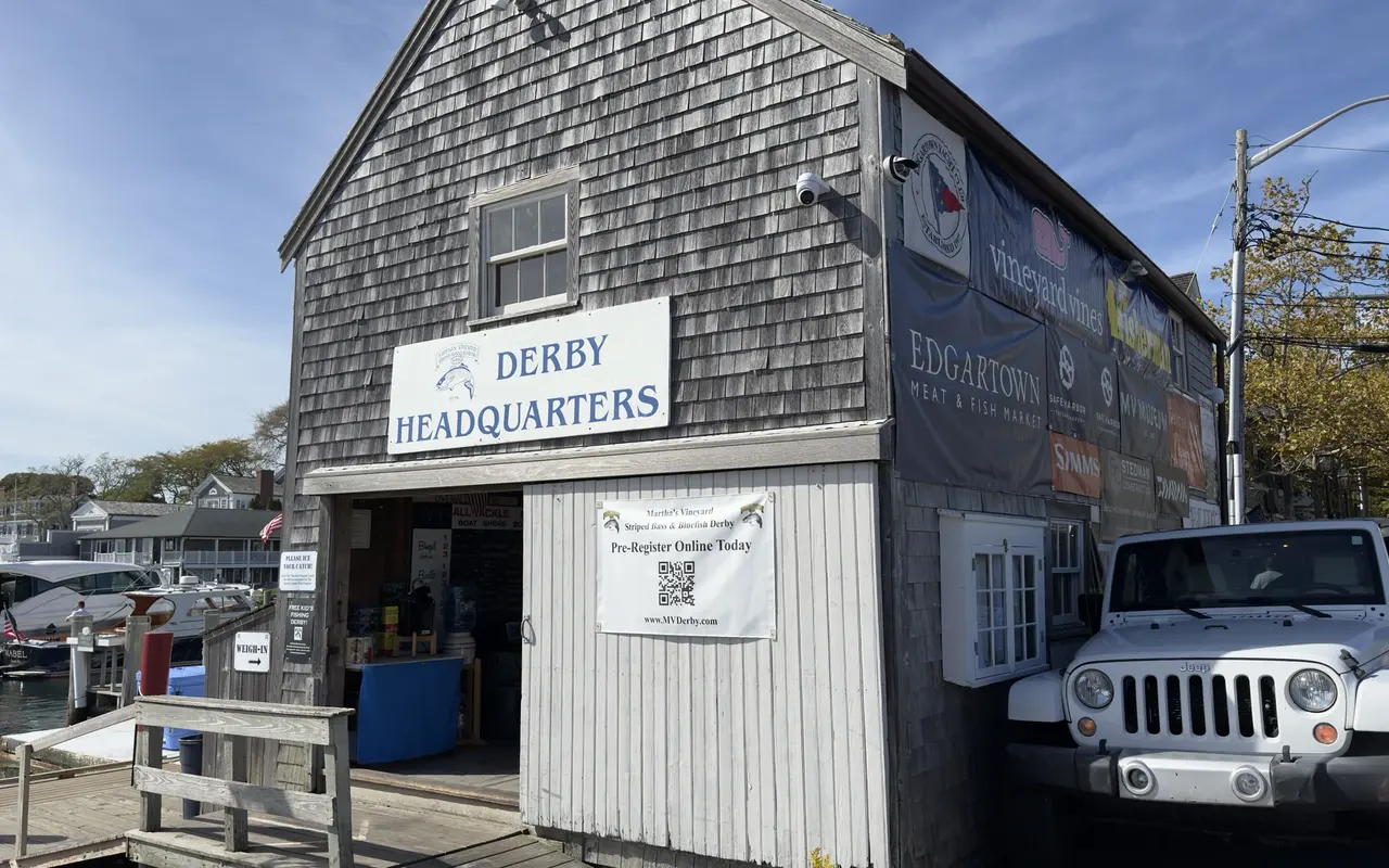Gray-shingled Derby Headquarters building on the Edgartown waterfront with its sign, an open door, a weigh-in arrow and a pre-registration banner