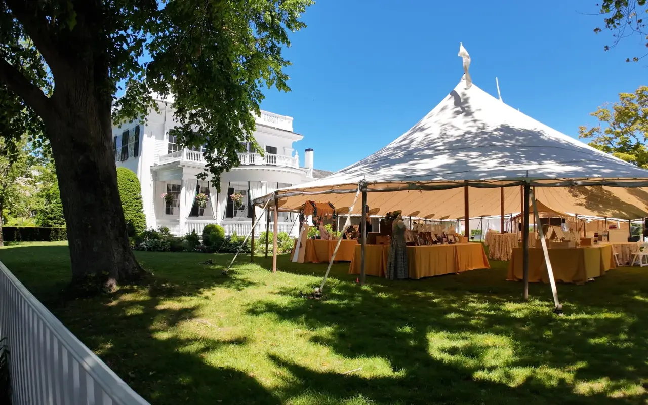 A white tent set up on the green lawn beside the Daniel Fisher House in Edgartown under a blue sky