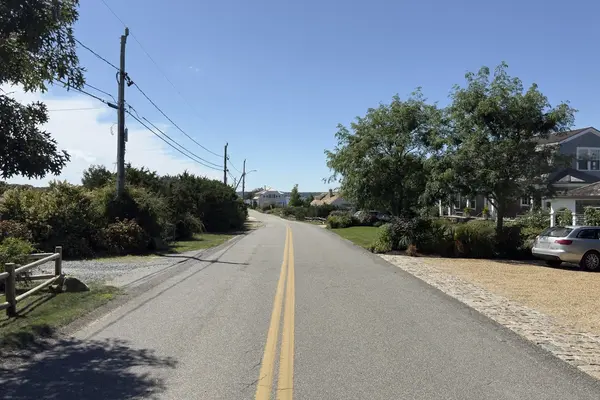 An East Chop road running toward the water between hedges and shingled houses