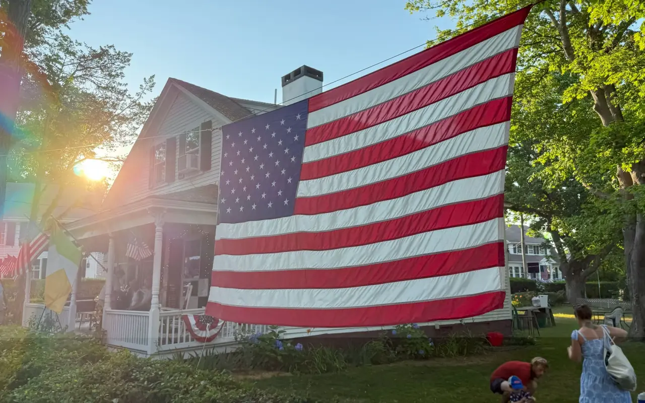 A very large American flag draped across the porch of a house in Edgartown