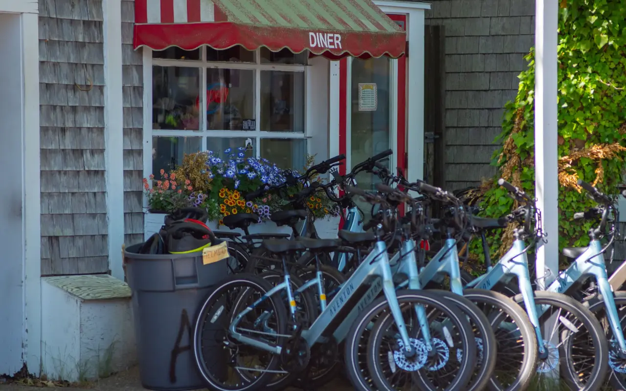 Row of rental e-bikes parked outside a shop with a striped awning in Edgartown