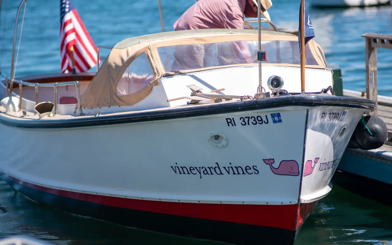 A white wooden launch with the Vineyard Vines whale logo tied up at a dock in Edgartown harbor