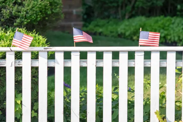Small American flags tucked into a white picket fence for the Fourth of July in Edgartown