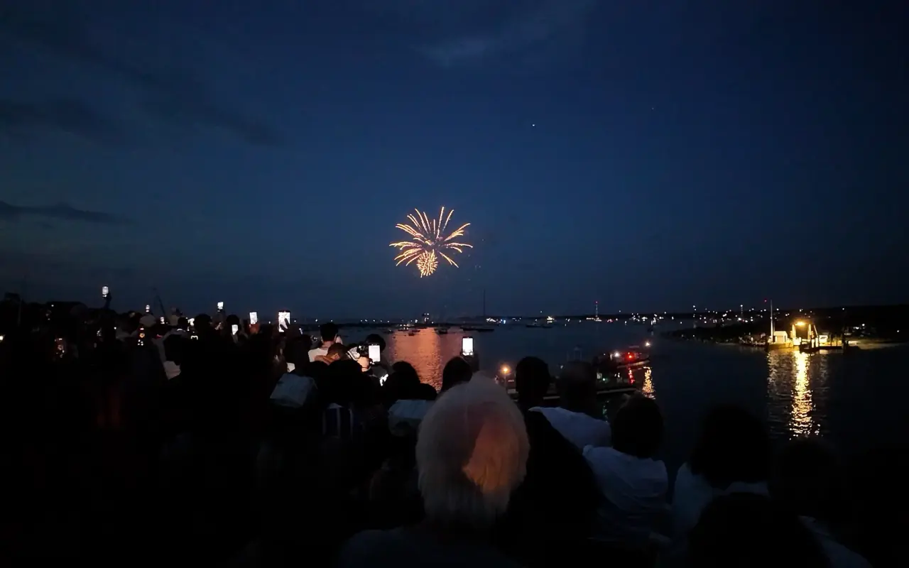 Fireworks bursting over Edgartown harbor at night with the crowd in silhouette