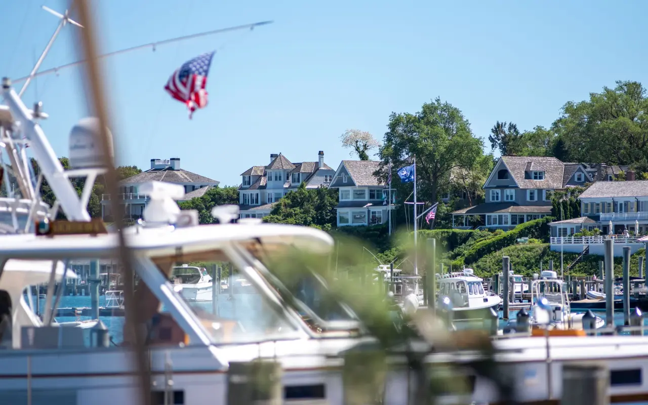 Sailboat masts and docks in Edgartown Harbor with houses behind