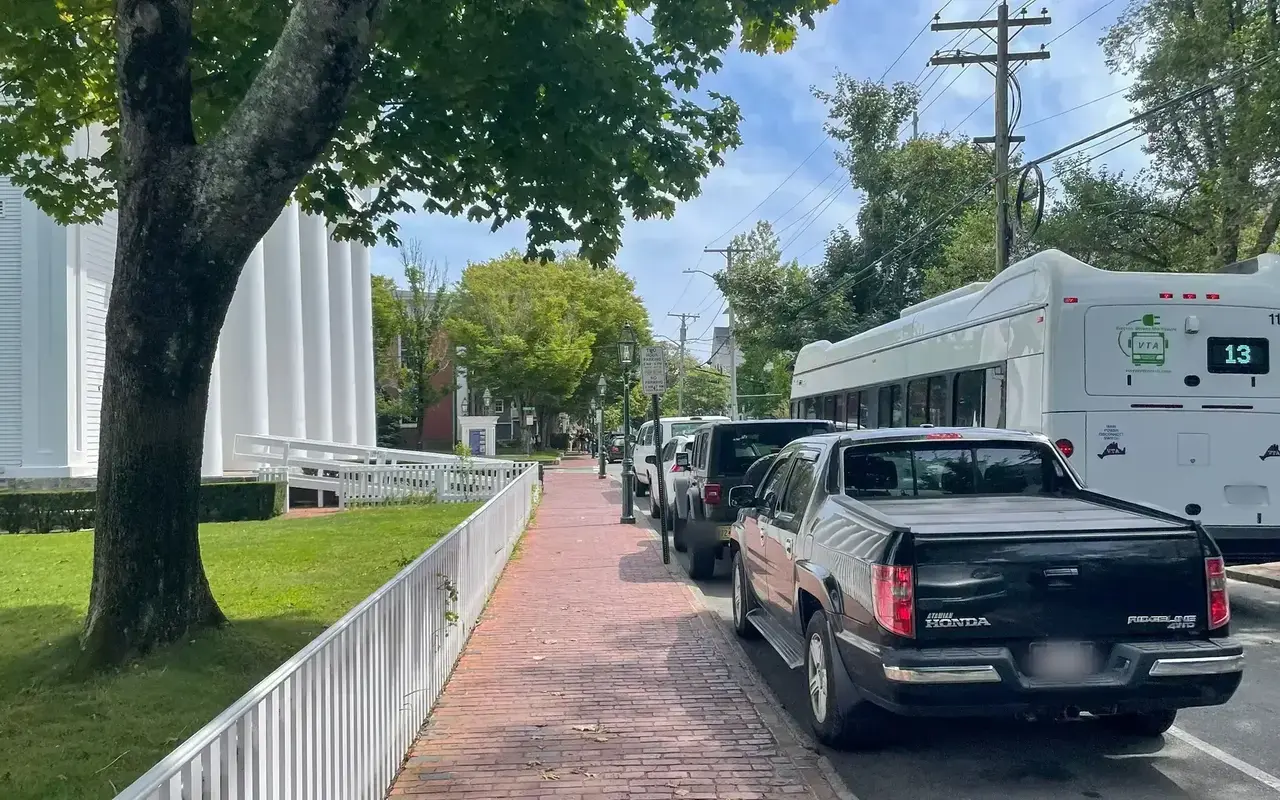 A VTA bus on Main Street in Edgartown beside a brick sidewalk and white church columns