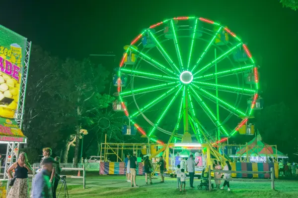 The Ferris wheel glows green over the midway after dark