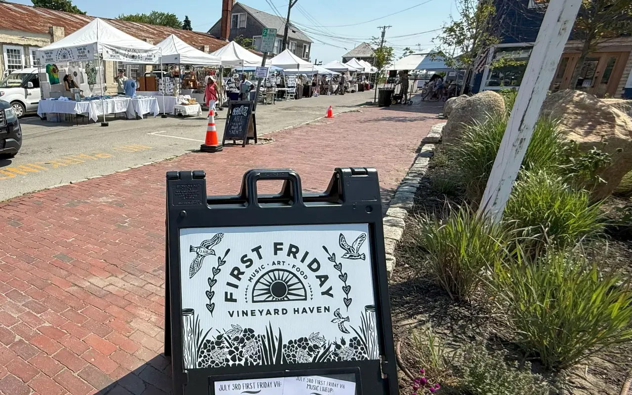 First Friday street festival sign on Main Street in Vineyard Haven with vendor tents beyond