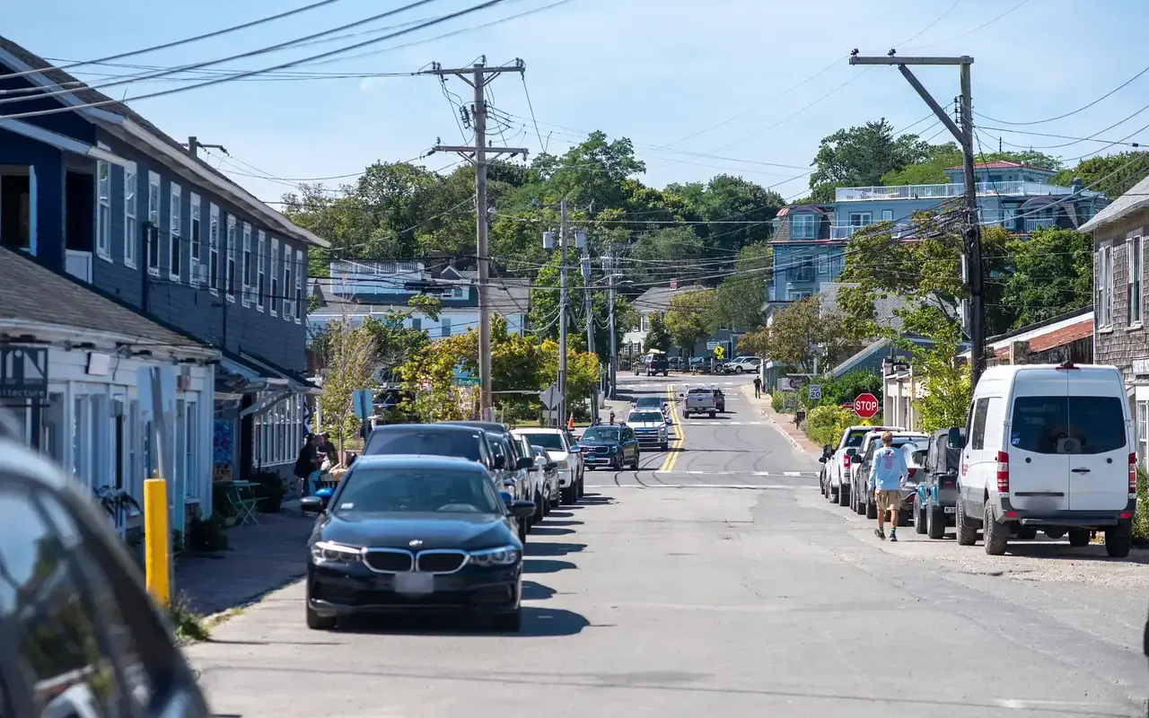 Street in Vineyard Haven with parked cars on both sides, a pedestrian and a stop sign ahead