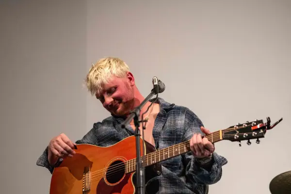 Garrett Owens, head down over a sunburst acoustic