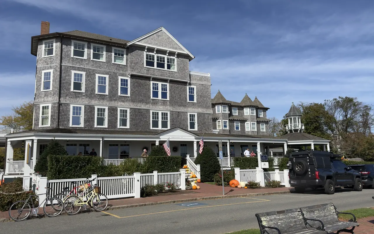 The gray-shingled Harbor View Hotel in Edgartown with its white wraparound porch, picket fence, American flags, pumpkins on the steps and bicycles parked out front