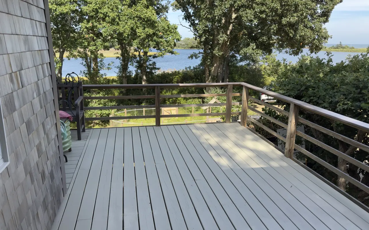 A wooden deck in Harthaven, Oak Bluffs, with oaks, the water and the far shore beyond the rail