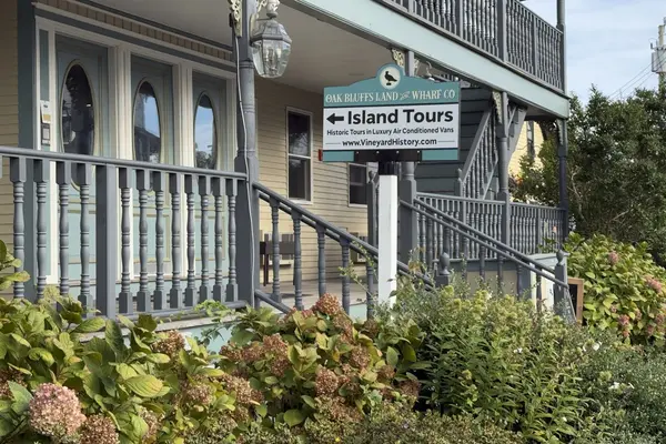 The Island Tours sign in front of a yellow Victorian porch in Oak Bluffs