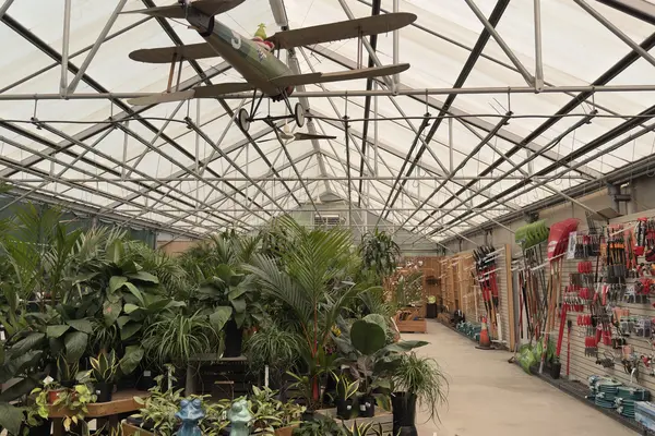 Inside the greenhouse at Jardin Mahoney garden center on Edgartown-Vineyard Haven Road: houseplants, the tool wall and a model biplane in the rafters