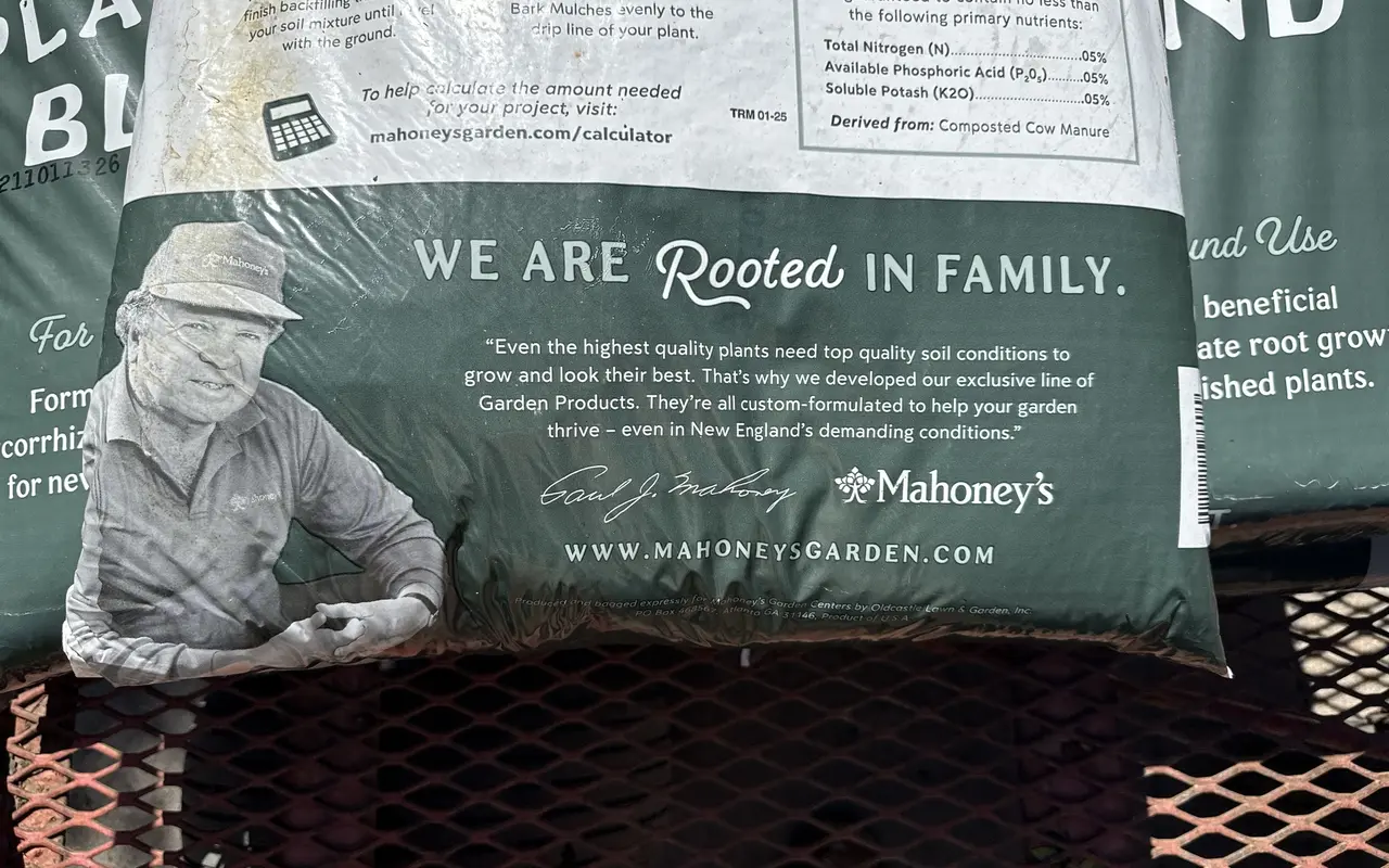 A bag of Mahoney's compost planting blend on a metal cart at Jardin Mahoney in Oak Bluffs, printed with the words We Are Rooted in Family
