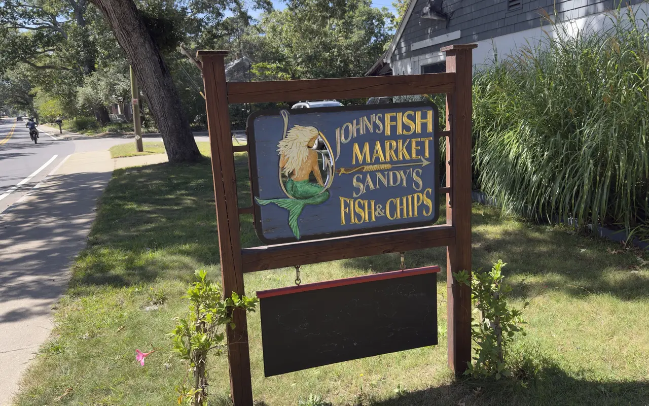 Carved roadside sign in Vineyard Haven with a mermaid on a fish hook for John's Fish Market and Sandy's Fish and Chips