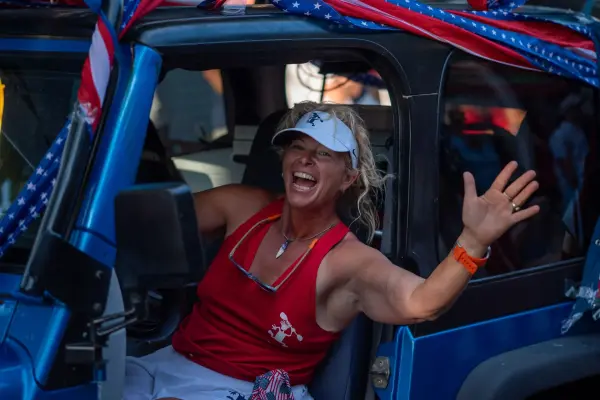 A laughing paddler waving from the Island Spirit Jeep in the Edgartown Fourth of July parade
