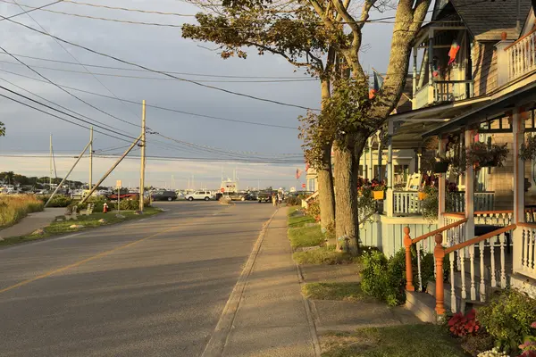 Lake Avenue at golden hour, cottage porches on one side and the harbor masts ahead
