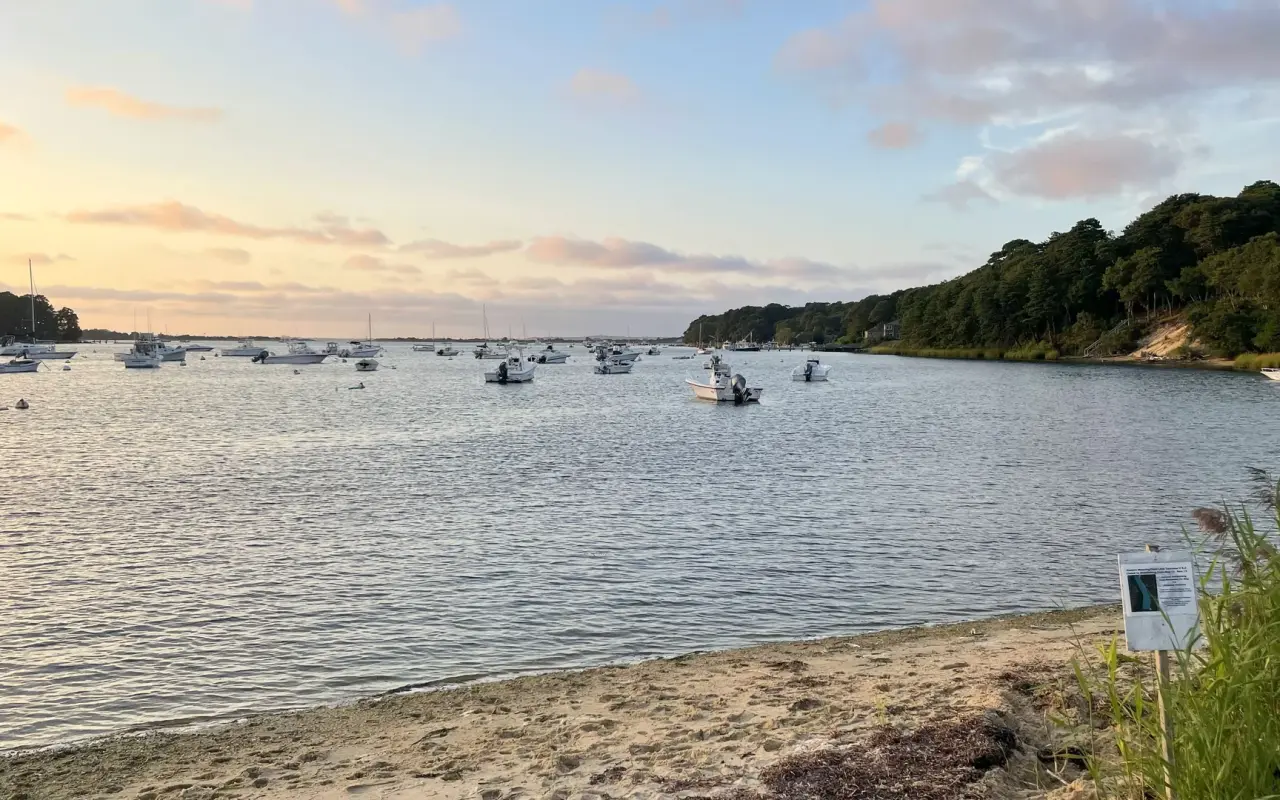 Moored boats on Lake Tashmoo in Vineyard Haven with the beach and the opening to the Sound beyond