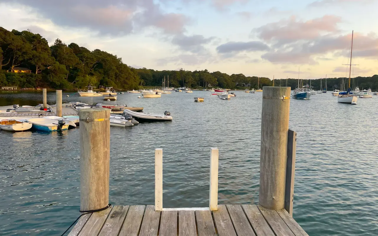 Wooden dock with a ladder on Lake Tashmoo, small boats moored on calm water
