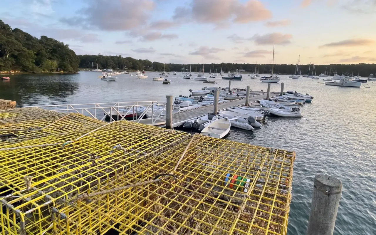 Yellow lobster traps stacked on the Lake Street pier with floating dinghy docks and moored boats on Lake Tashmoo