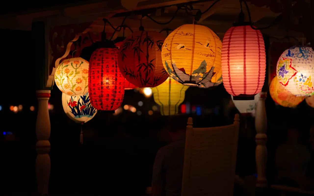 Paper lanterns glowing on a gingerbread cottage porch at night in Oak Bluffs