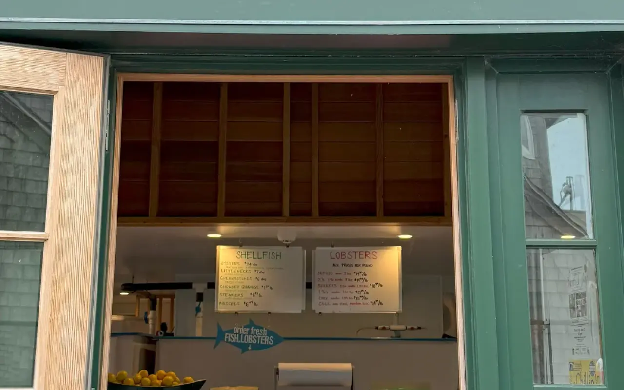 Order window at Larsen’s Fish Market with handwritten shellfish and lobster price boards