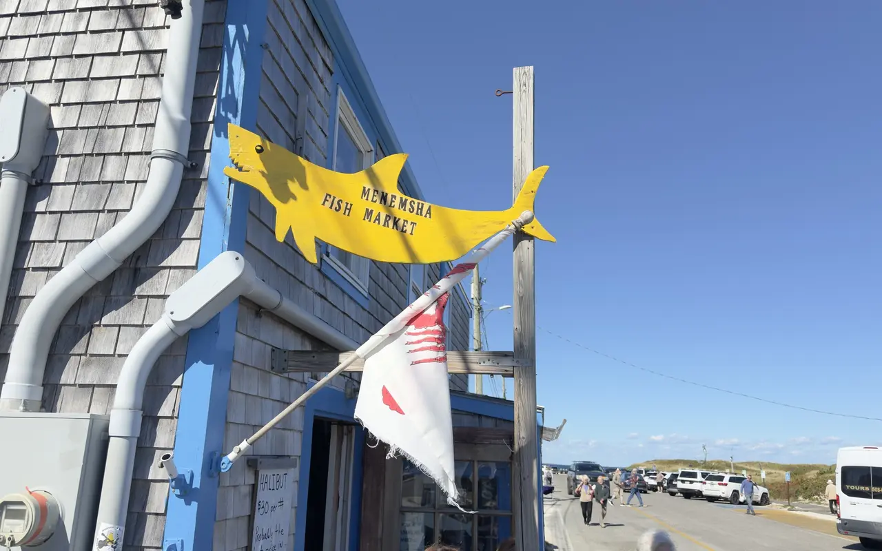 Yellow and white fish-shaped signs on the shingled corner of the Menemsha Fish Market