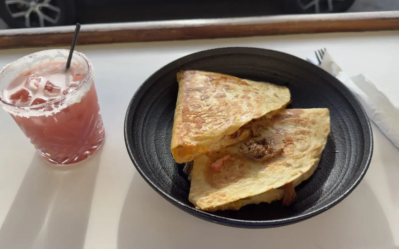 A quesadilla in a black bowl and a salt-rimmed pink drink on the counter at Midnight Taco