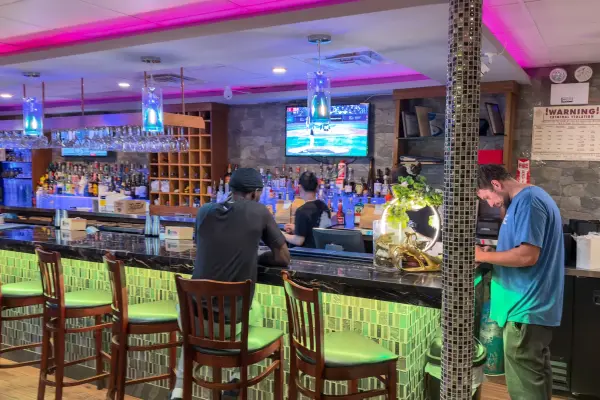 The bar at Mikado Asian Bistro glowing green and pink on a summer evening.