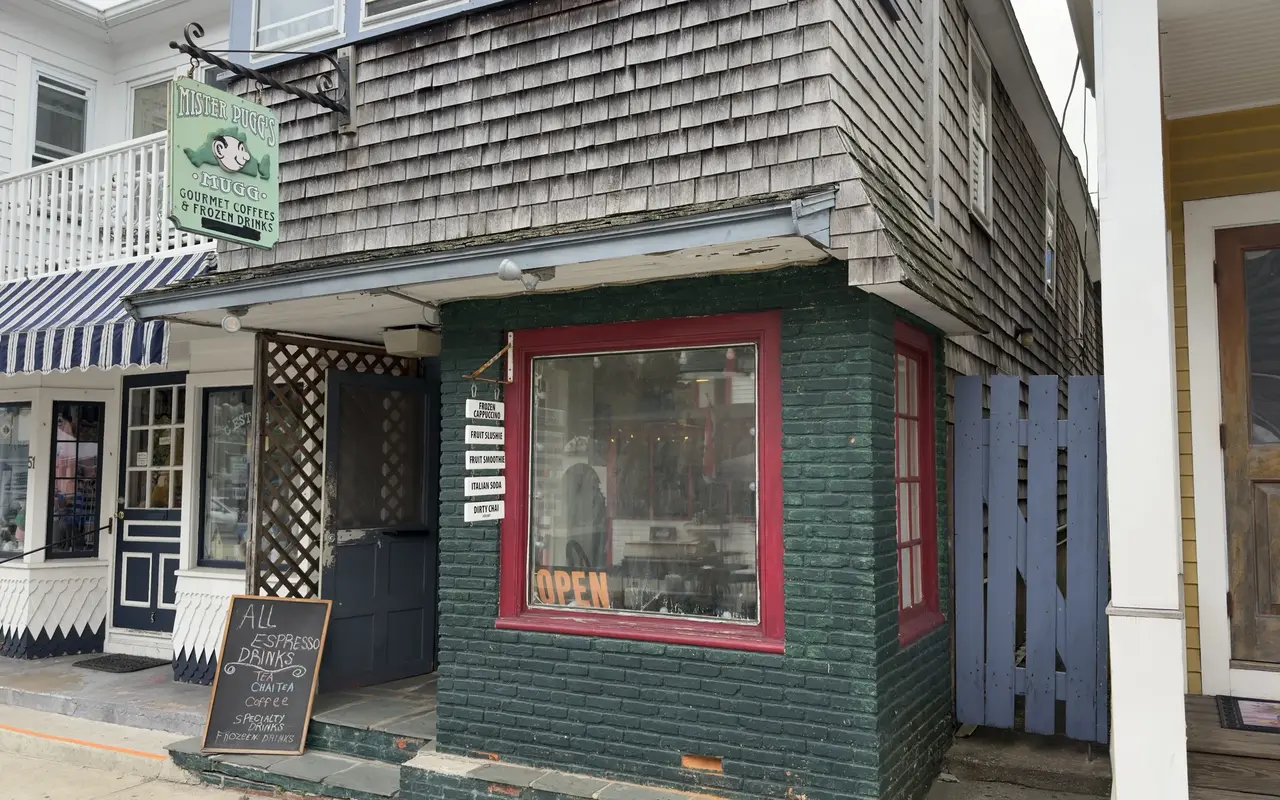 The corner of Mister Pugg's Mugg in Oak Bluffs: shingled upper floor, green brick below, red window frames and the hanging Gourmet Coffees and Frozen Drinks sign